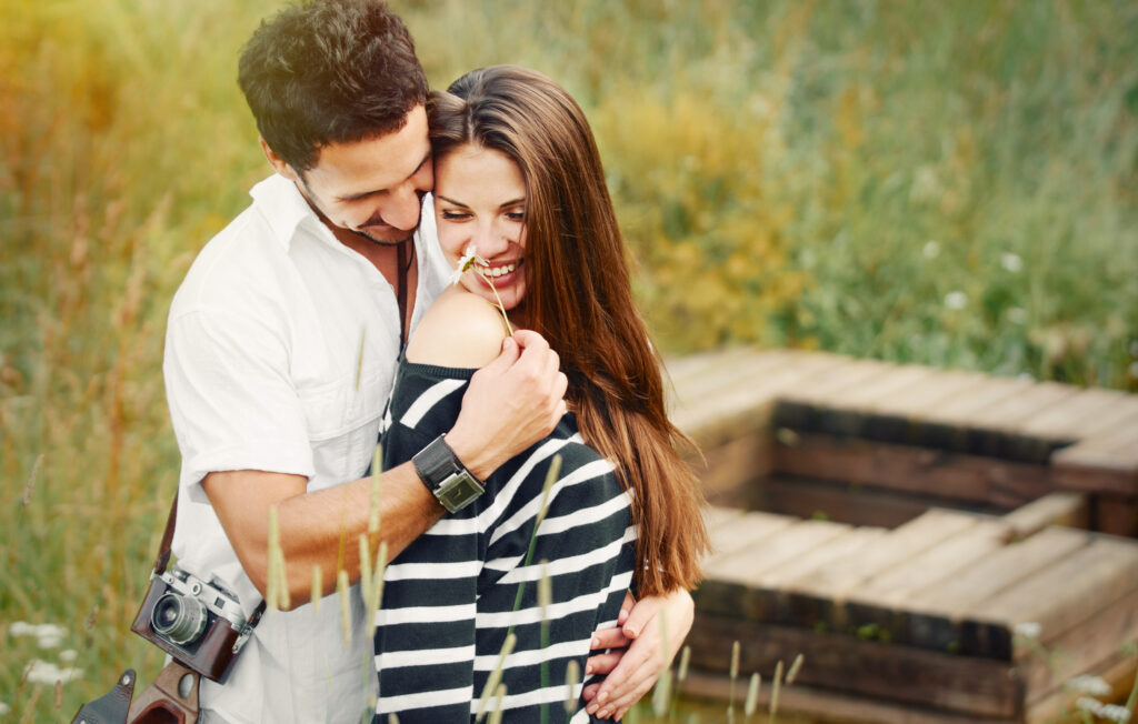 Liebespaar, happy romantic couple in love and having fun with daisy at the lake outdoor in summer day, beauty of nature, harmony concept